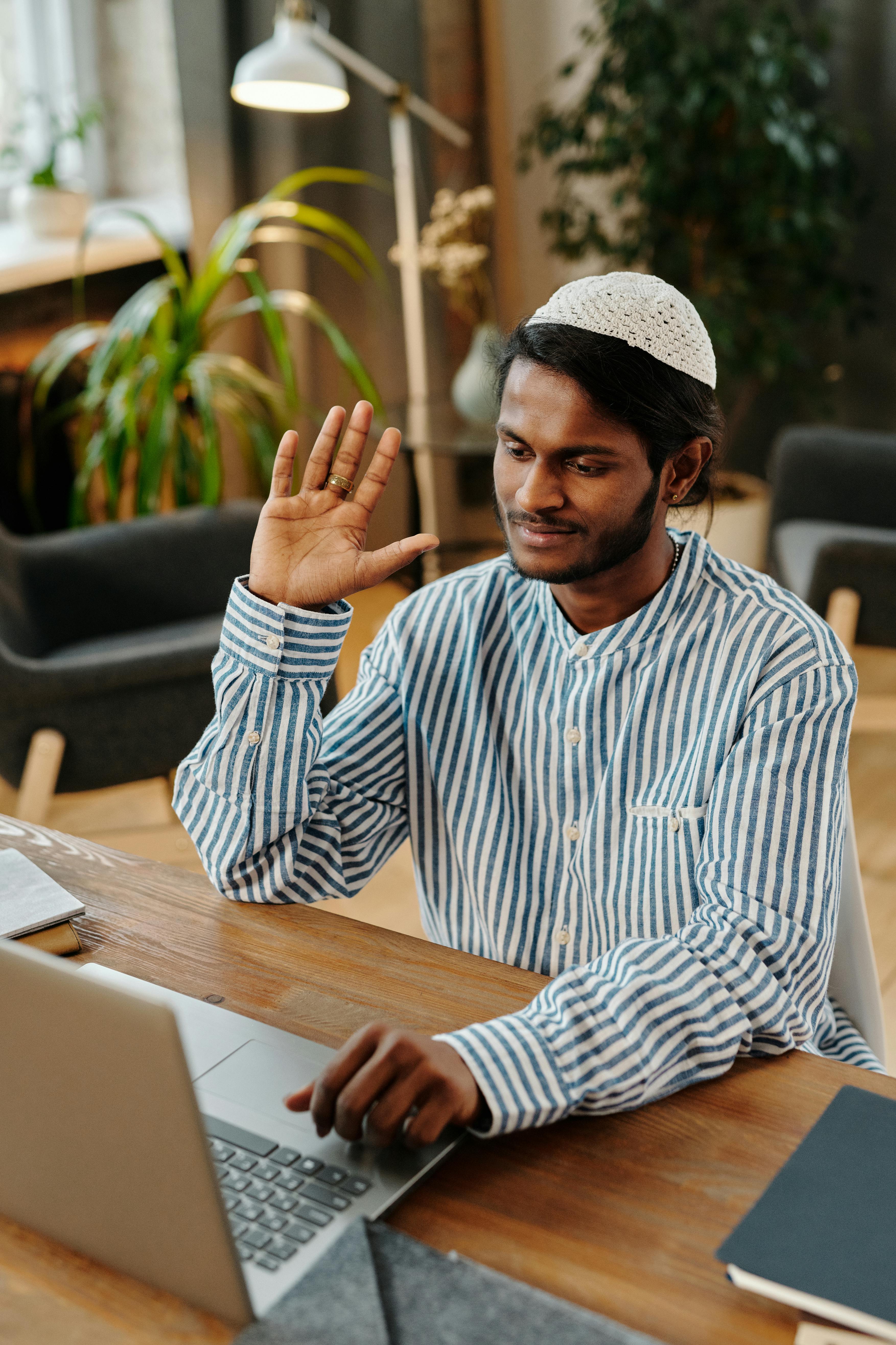 smiling man waving talking on webcam on computer