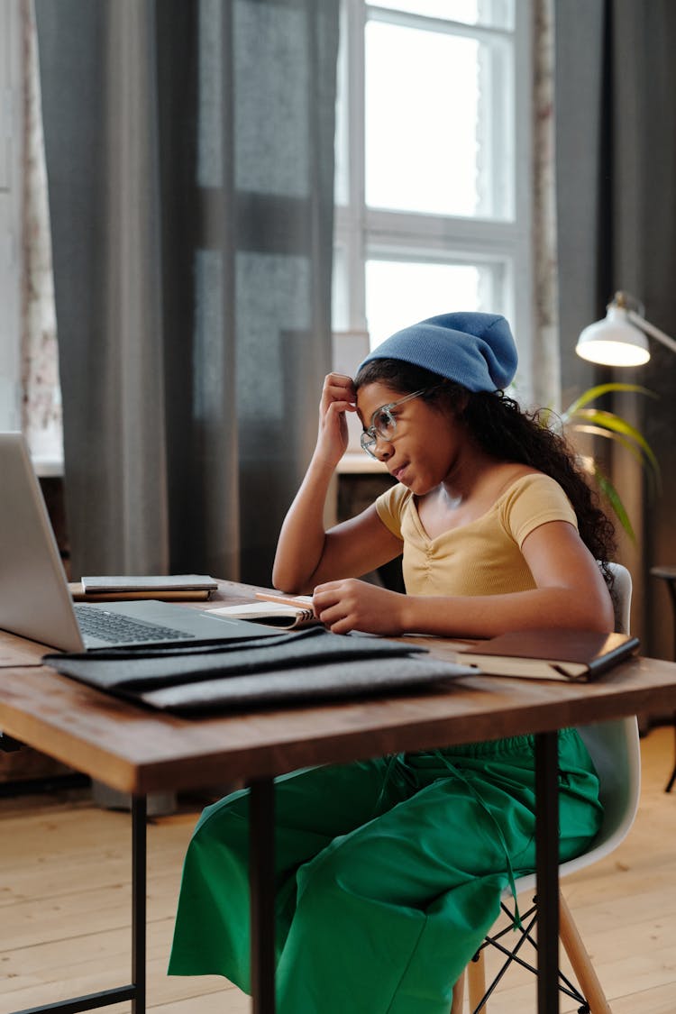 A Young Girl Sitting While Facing The Laptop