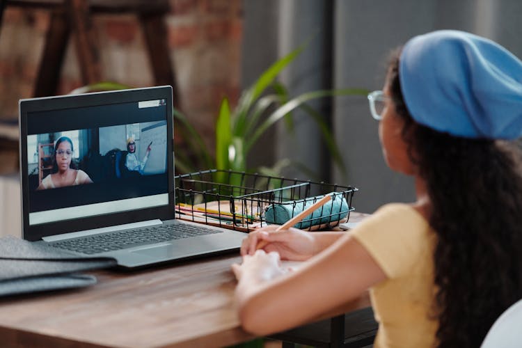 A Woman Wearing A Beanie While Looking At The Laptop Screen