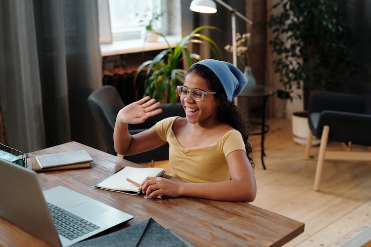 A Young Girl In Yellow Top Smiling While Looking At The Laptop