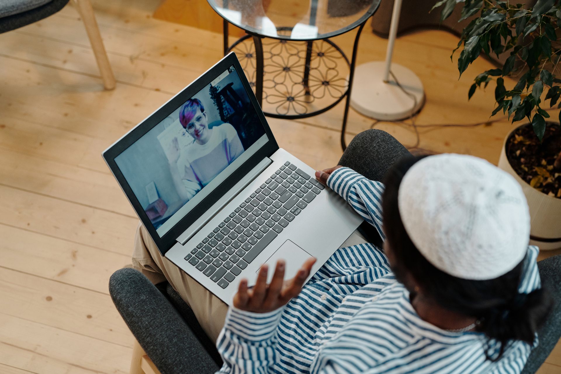 Person using a laptop for a video call indoors, demonstrating remote communication technology.