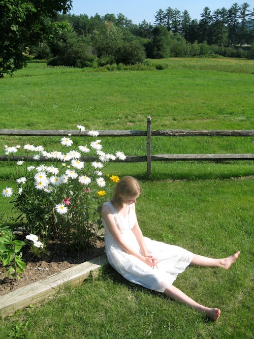 Woman in a White Summer Dress Sitting on Grass 