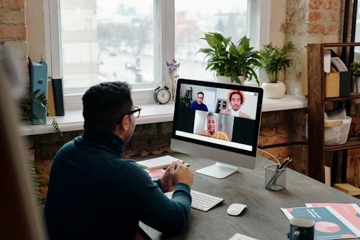 Man participating in video call at desktop computer in stylish office setting with greenery.