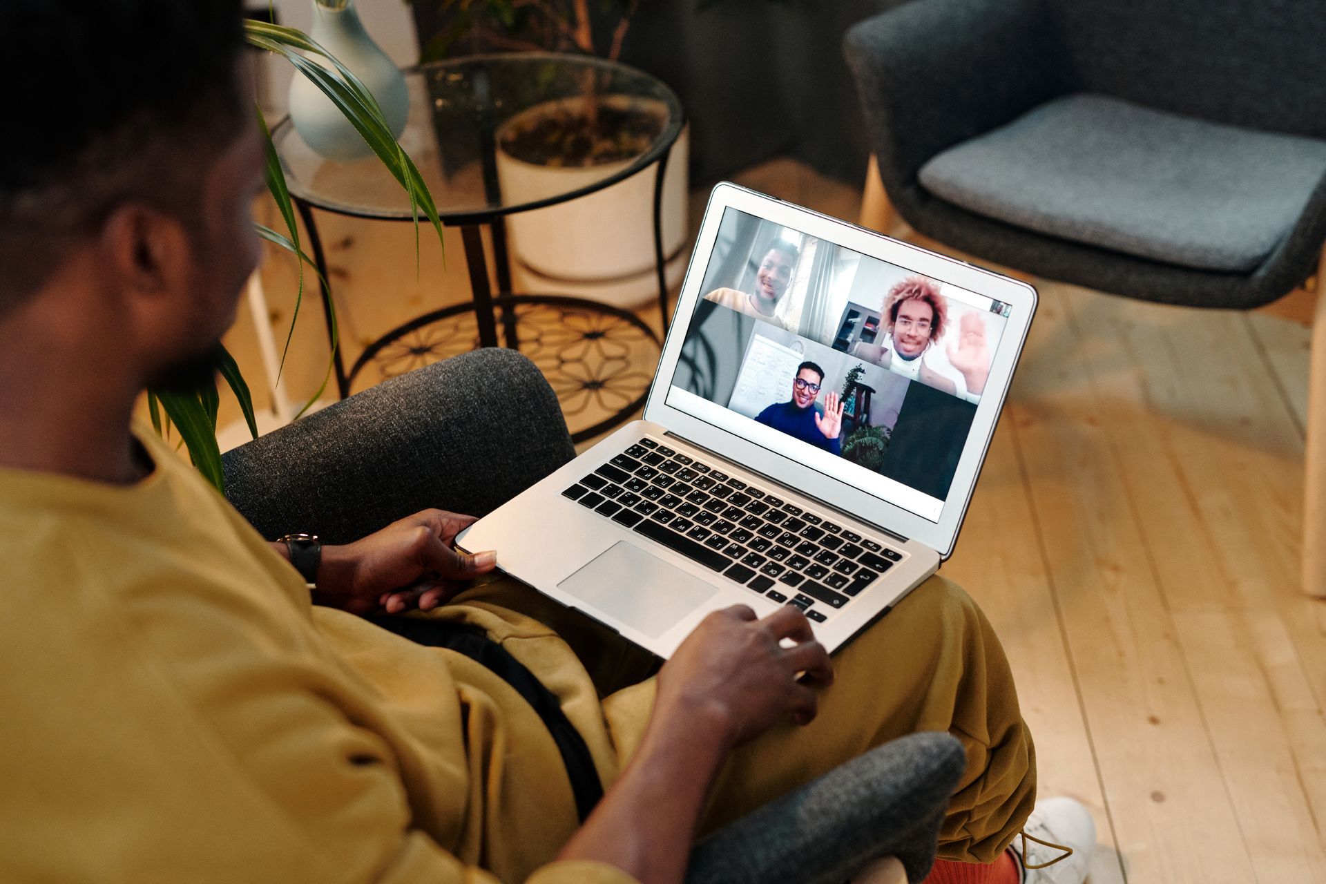 Person sitting in a chair using laptop for a virtual meeting in a cozy home office setting.