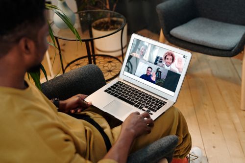 Free Person sitting in a chair using laptop for a virtual meeting in a cozy home office setting. Stock Photo