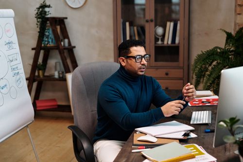 Free Focused businessman in glasses working on computer with documents in a sleek office. Stock Photo