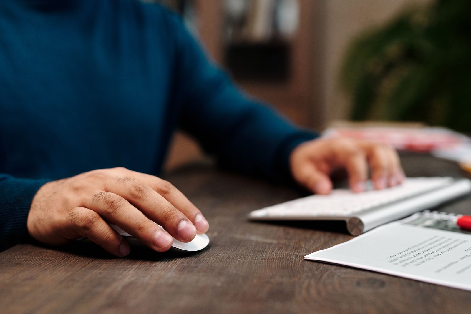 Close-up of a hand clicking a computer mouse beside a keyboard