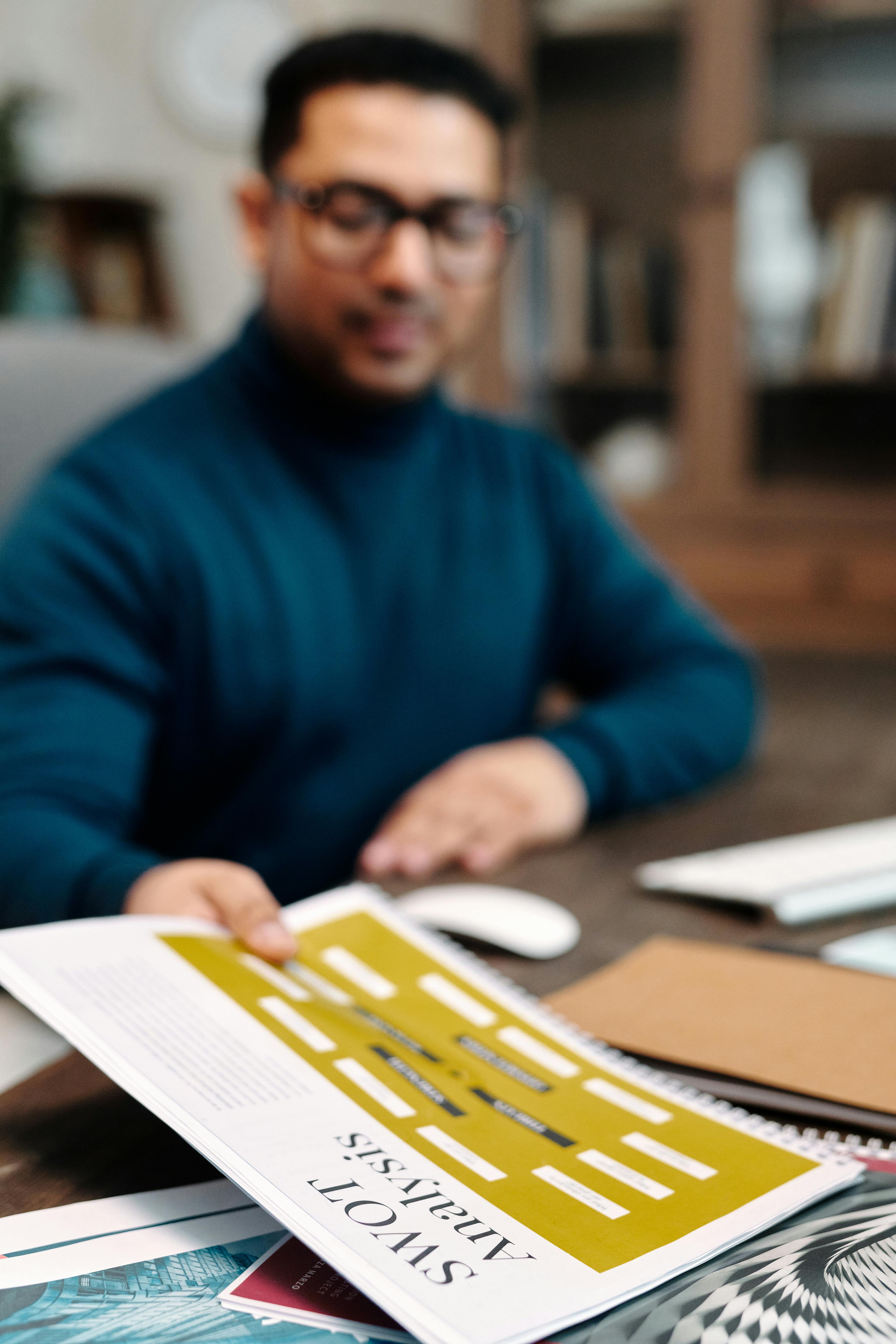 a man in long sleeve and eyeglasses holding a paper