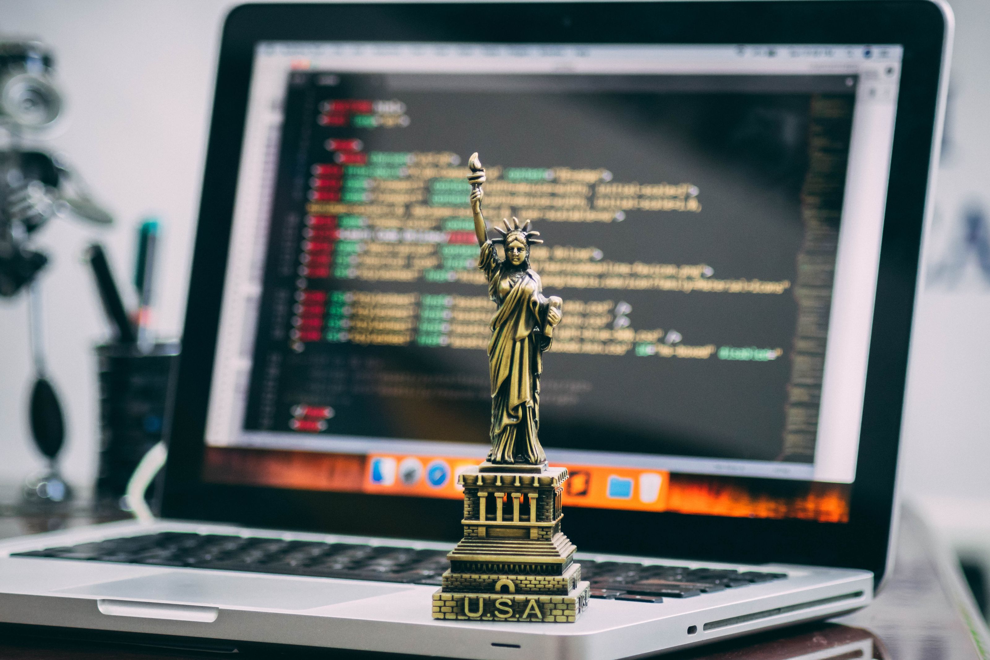 A miniature Statue of Liberty placed on a laptop displaying code, symbolizing freedom in technology.