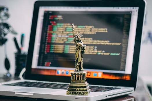 笔记本电脑上放置着一座微型自由女神像，显示着代码，象征着技术自由