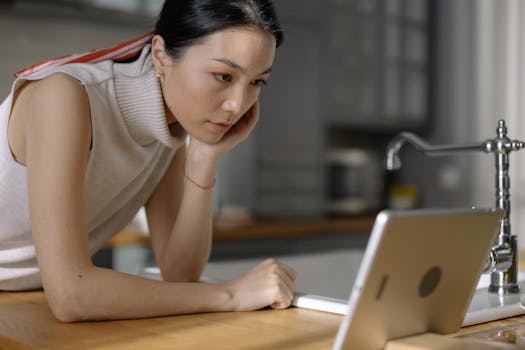 An engaged woman using a tablet device while leaning on a kitchen counter indoors.