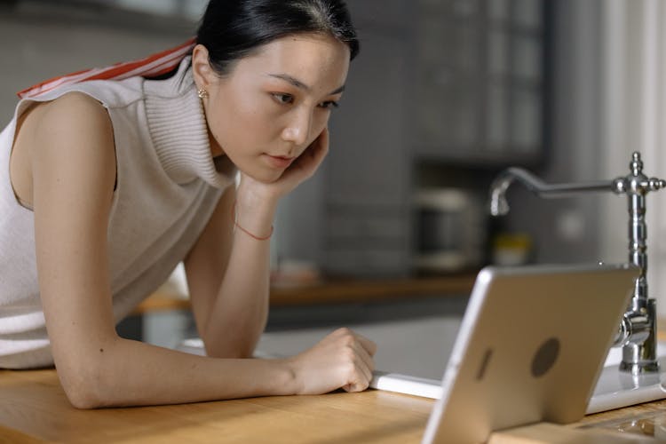 Woman Leaning On Table And Looking At Tablet