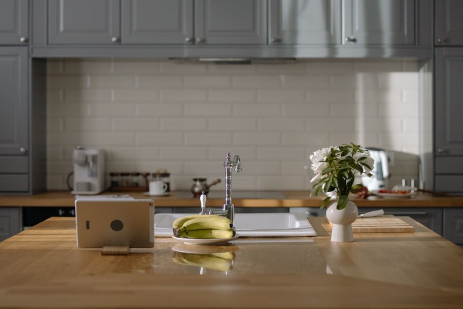 What Safety Research Reveals About Baby Proofing Cabinet Locks and Outlet Covers A minimalist kitchen with a wooden island, fresh bananas, and a digital tablet. Stylish interior design.