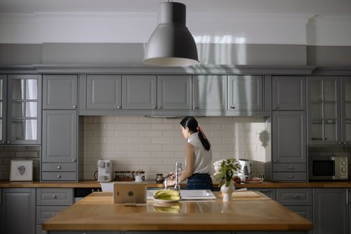 Free Woman cooking in a contemporary kitchen with gray cabinets and wooden countertops. Stock Photo