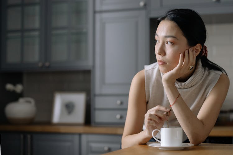 Woman In Sleeveless Shirt Stirring Her Drink