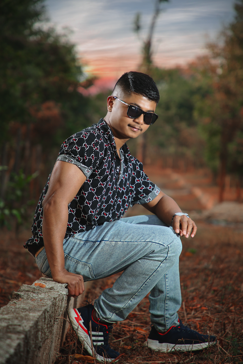 Free A fashionable young man in sunglasses posing outdoors during a colorful sunset. Stock Photo