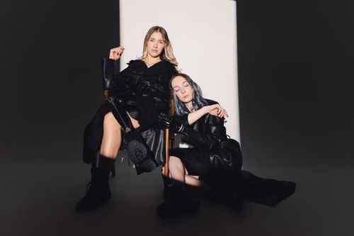 Free Two fashion models posing in stylish black attire under a dramatic spotlight. Stock Photo