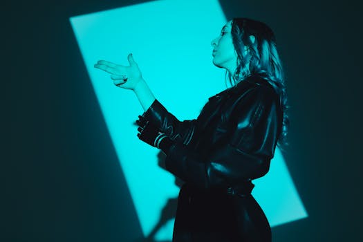 A woman in a black coat under blue light, showcasing modern fashion vibes.