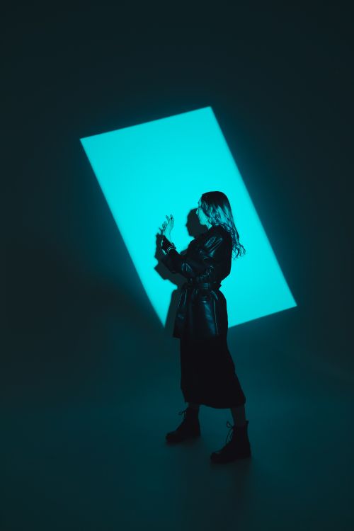 Free Artistic silhouette of a woman standing in a studio with blue light and shadows. Stock Photo