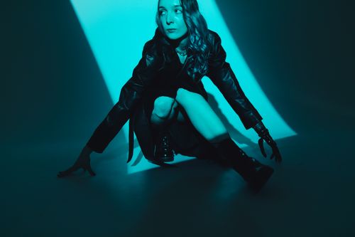 Free Fashionable woman posing in dramatic blue lighting. Stylish and modern aesthetic with leather wear. Stock Photo