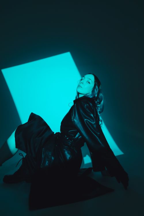 Free Artistic shot of a fashionable woman in black leather jacket posing under dramatic lighting. Stock Photo