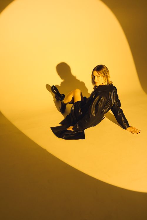 Free Fashionable woman in a leather jacket sitting in dramatic lighting. Stock Photo