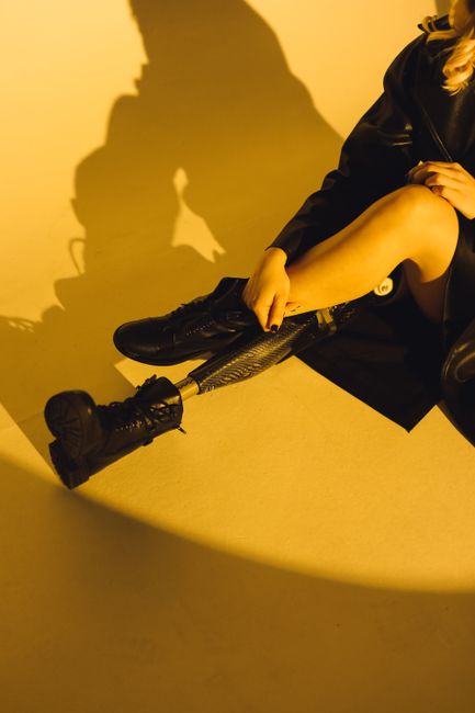Portrait of a stylish woman with a prosthetic leg wearing a black leather jacket and boots, embodying modern fashion.