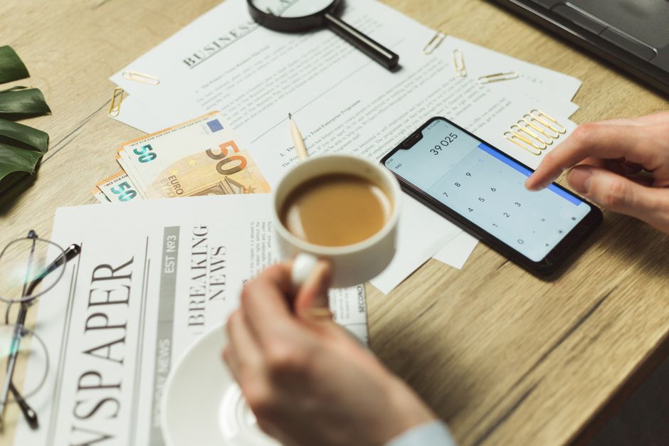 How to Write 10 Pages Overnight: A Realistic Survival Guide 2 High-angle view of a business workspace with documents, coffee, currency, and smartphone calculator.