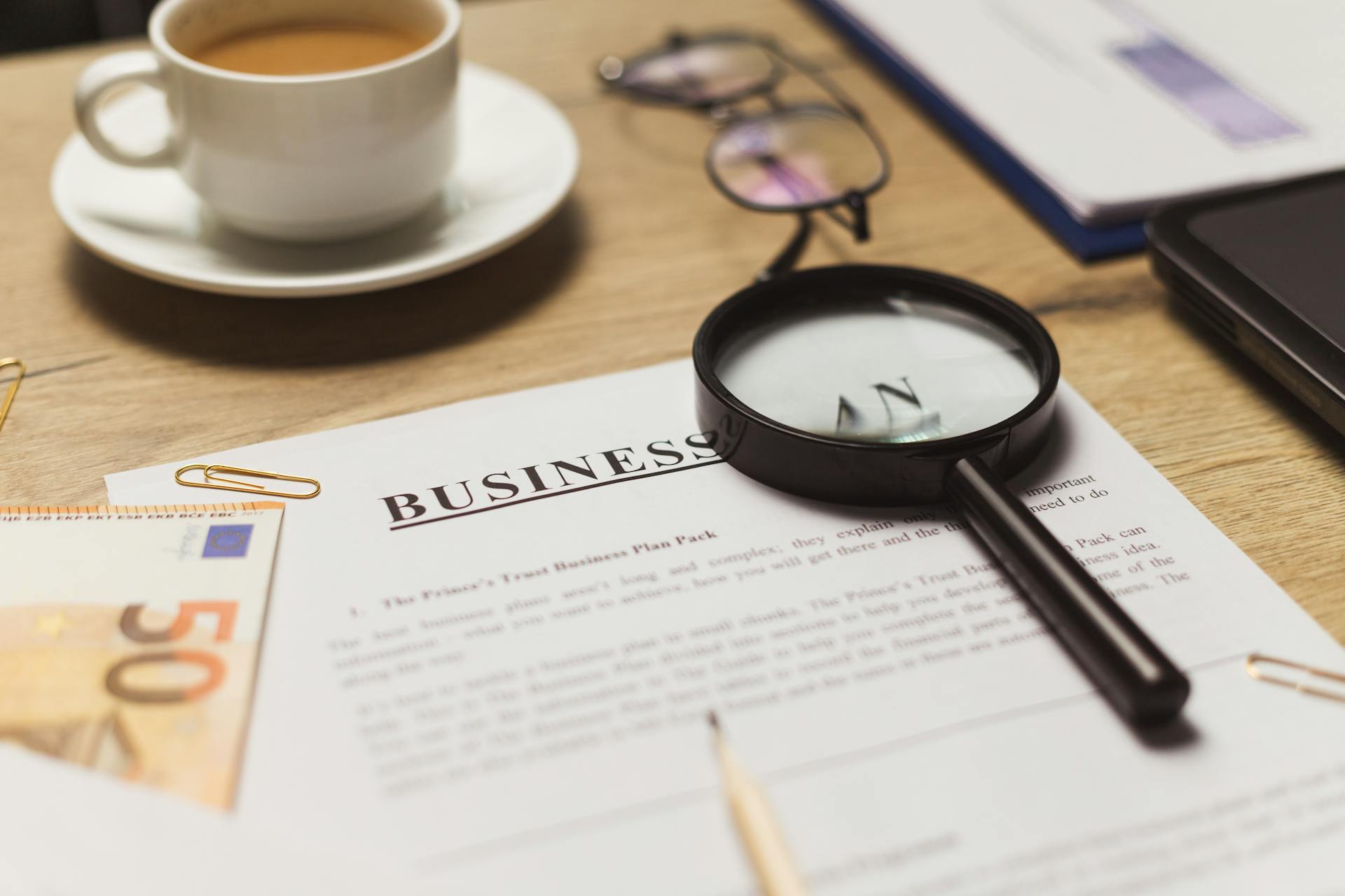 A business workspace setup featuring documents, coffee, and financial elements.