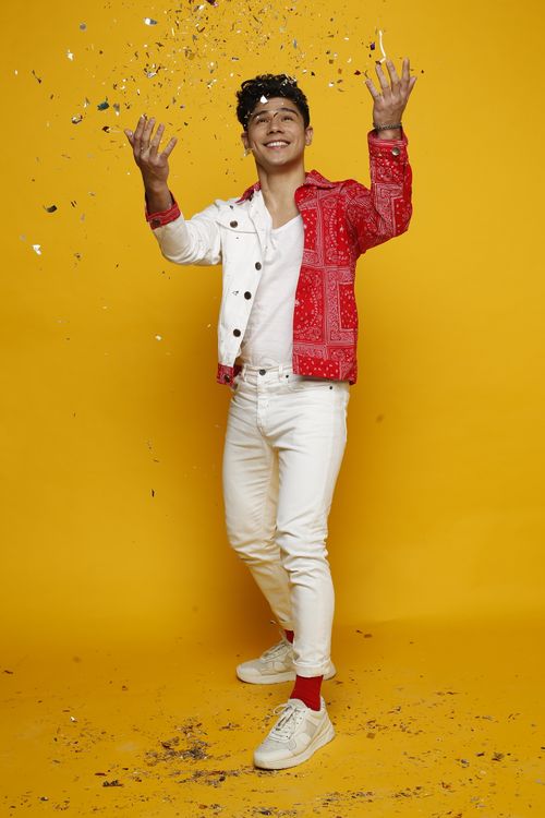 Free Smiling man in colorful streetwear joyfully throwing confetti against a vibrant yellow background. Stock Photo