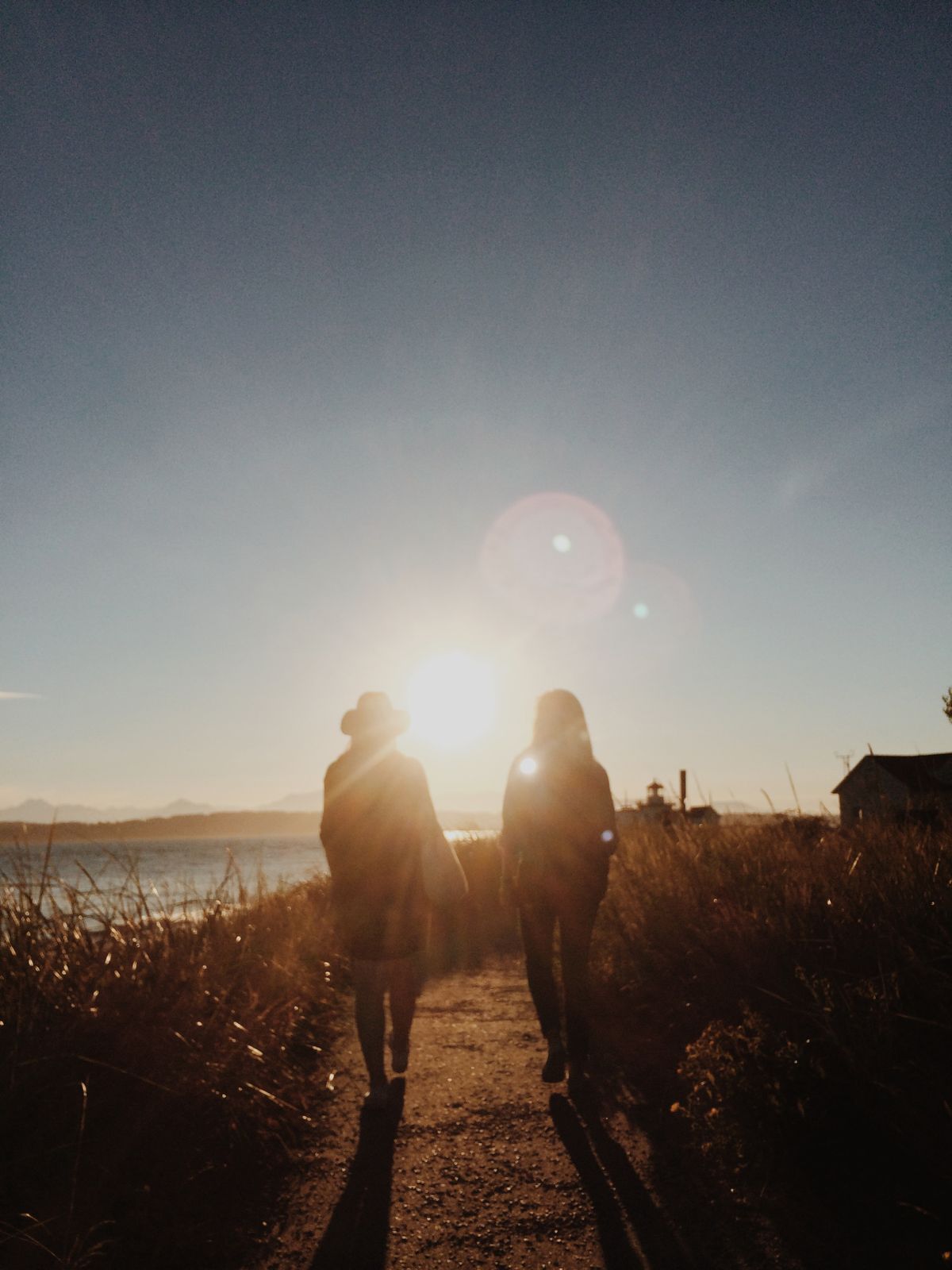 Dos personas caminando juntas hacia el atardecer