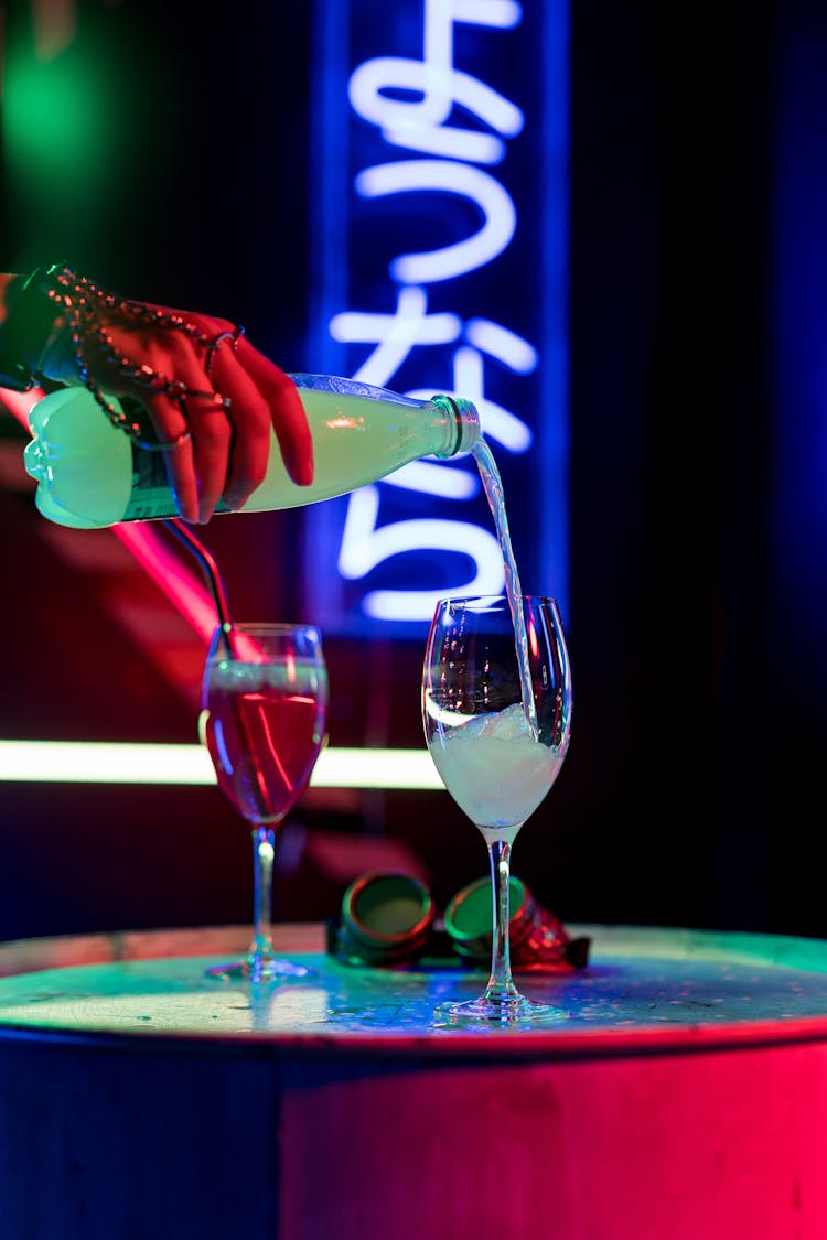 A Person Pouring Cocktail Into The Wine Glass