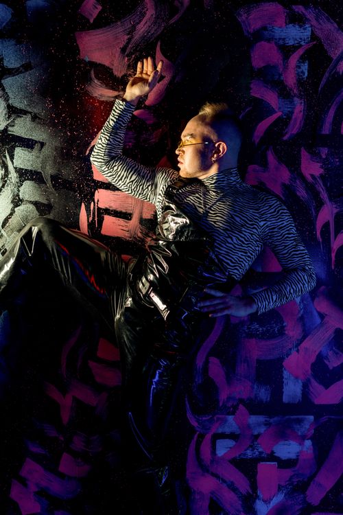 Free Male model in animal print and leather pants poses against neon graffiti backdrop. Stock Photo