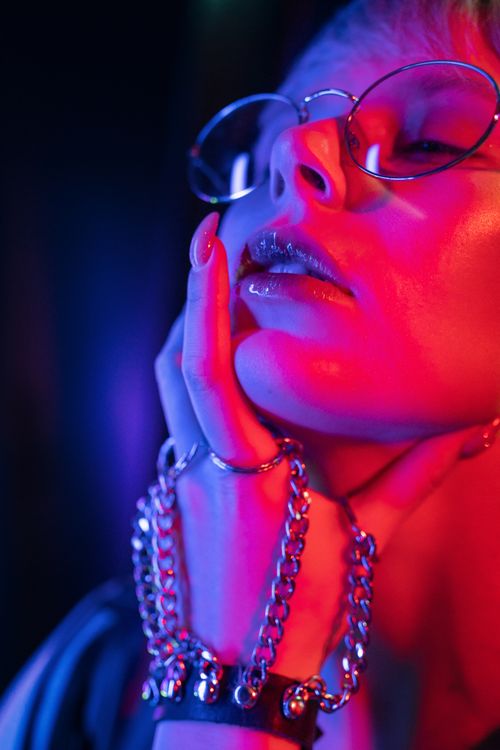 Free Close-up portrait of a woman with eyeglasses and chains under red neon lights. Stock Photo