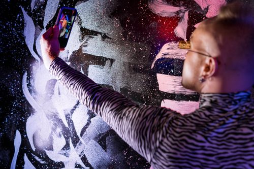 Free Man taking a cyberpunk-themed selfie against a vibrant graffiti wall. Stock Photo