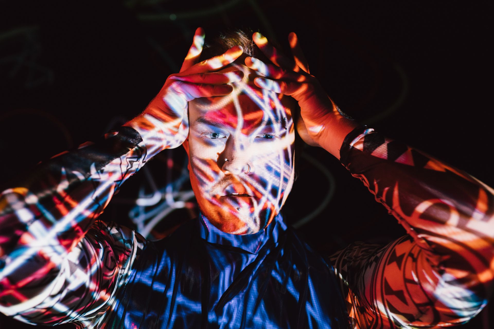 Vibrant portrait of a fashionable man with neon light projections and edgy pose.