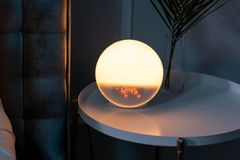 Sleek bedside table featuring a glowing orb alarm clock, perfect for a stylish bedroom.