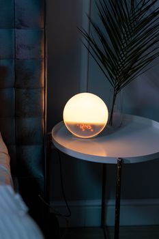 Sleek bedside table featuring a glowing orb alarm clock, perfect for a stylish bedroom.