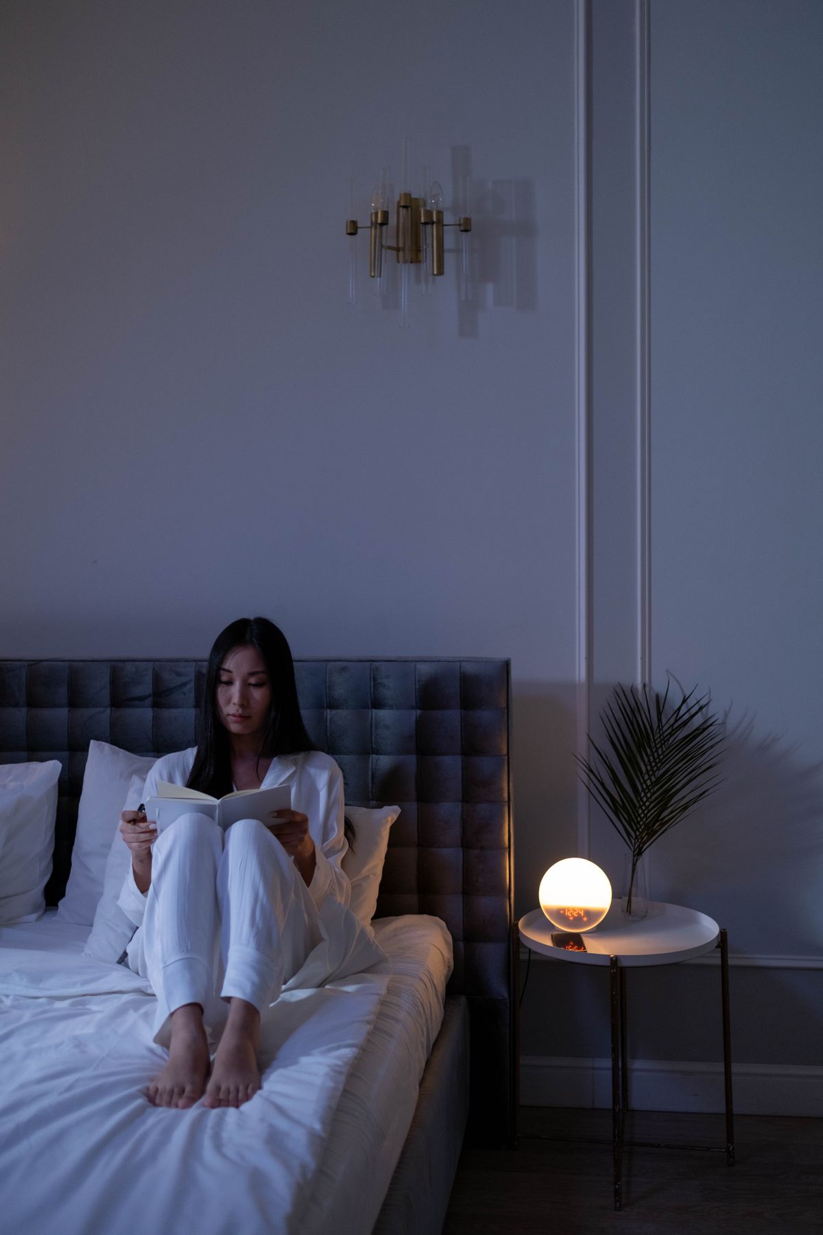 Woman reading a book in bed as part of a wind-down routine