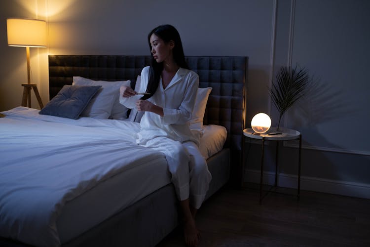 Woman In White Pajamas Brushing Her Hair