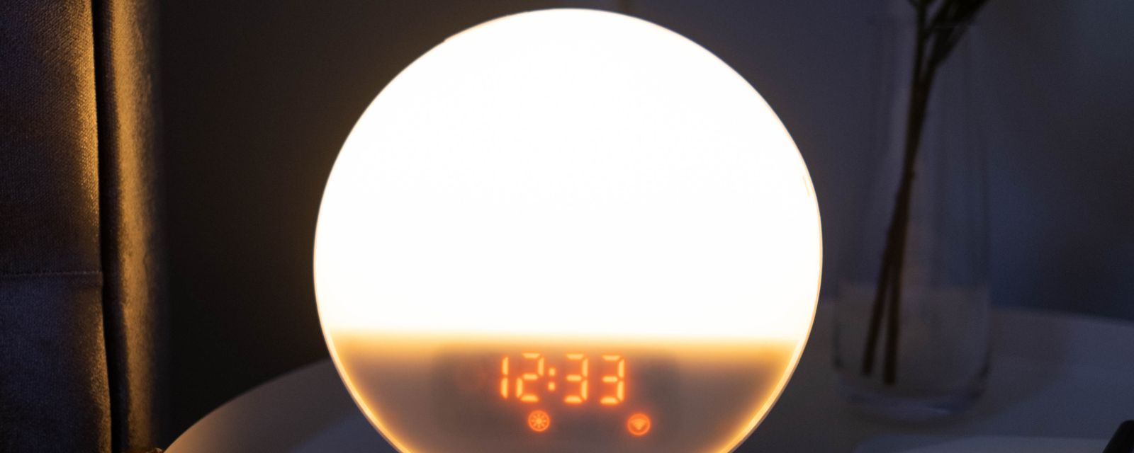 Glowing alarm clock and smartphone on a bedside table at night