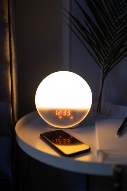 Minimalist side table with glowing alarm clock and smartphone at night, creating a cozy atmosphere.