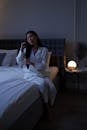 A Pretty Woman in White Sleepwear Sitting on a Bed