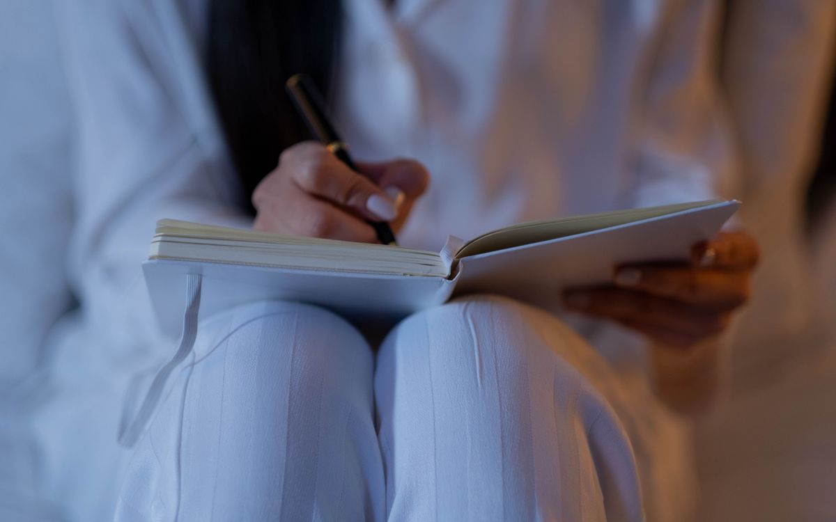 An intimate close-up of a person writing in a notebook, capturing a nighttime writing session.