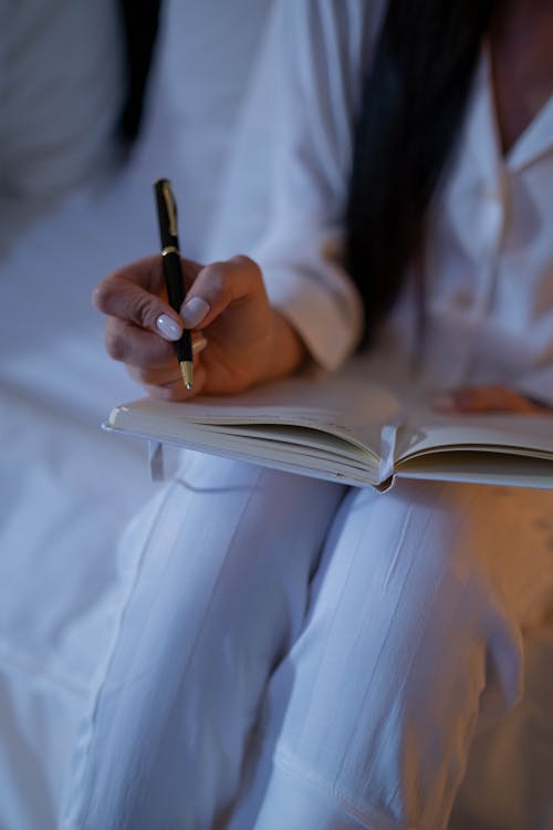 Close-Up Shot of a Person Writing on a Notebook