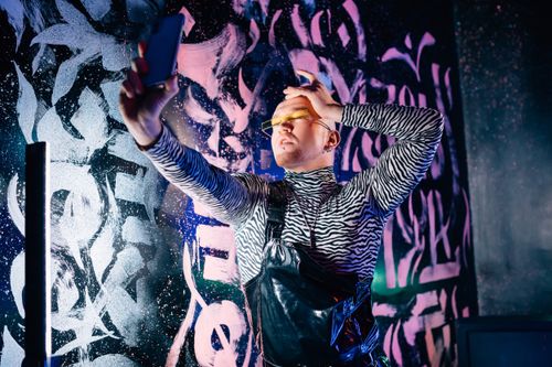 Free Fashion-forward individual posing for a selfie with vibrant graffiti backdrop. Stock Photo