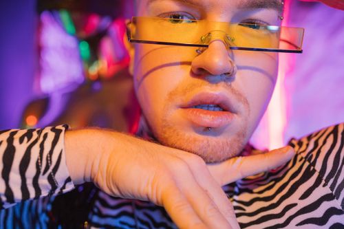 Free Close-up portrait of a fashionable man wearing zebra print and yellow glasses in vibrant lighting. Stock Photo