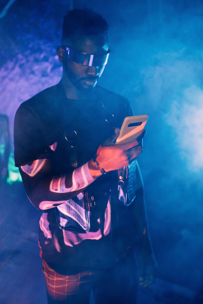 Tech-savvy young man wearing futuristic glasses using a smartphone in a neon-lit cyberpunk setting