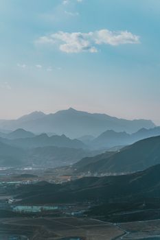 Peaceful landscape with overlapping mountain ranges under a clear blue sky.