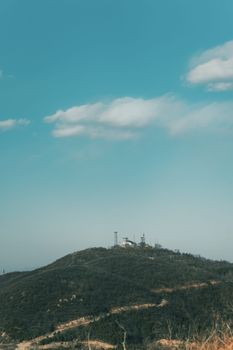 Telecommunication towers on a hilltop set against a clear blue sky, showcasing wireless communication.